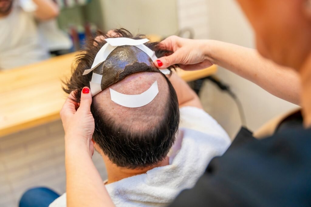 Hairstylist attaching a wig to a man using adhesive stripes