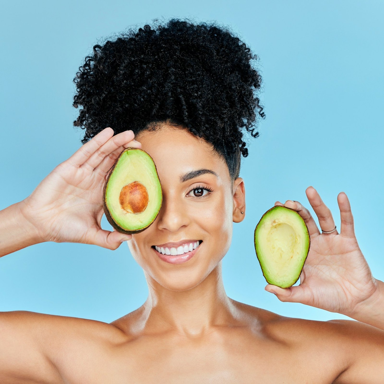 Happy woman, portrait and avocado for skincare, diet or natural beauty against a blue studio backgr